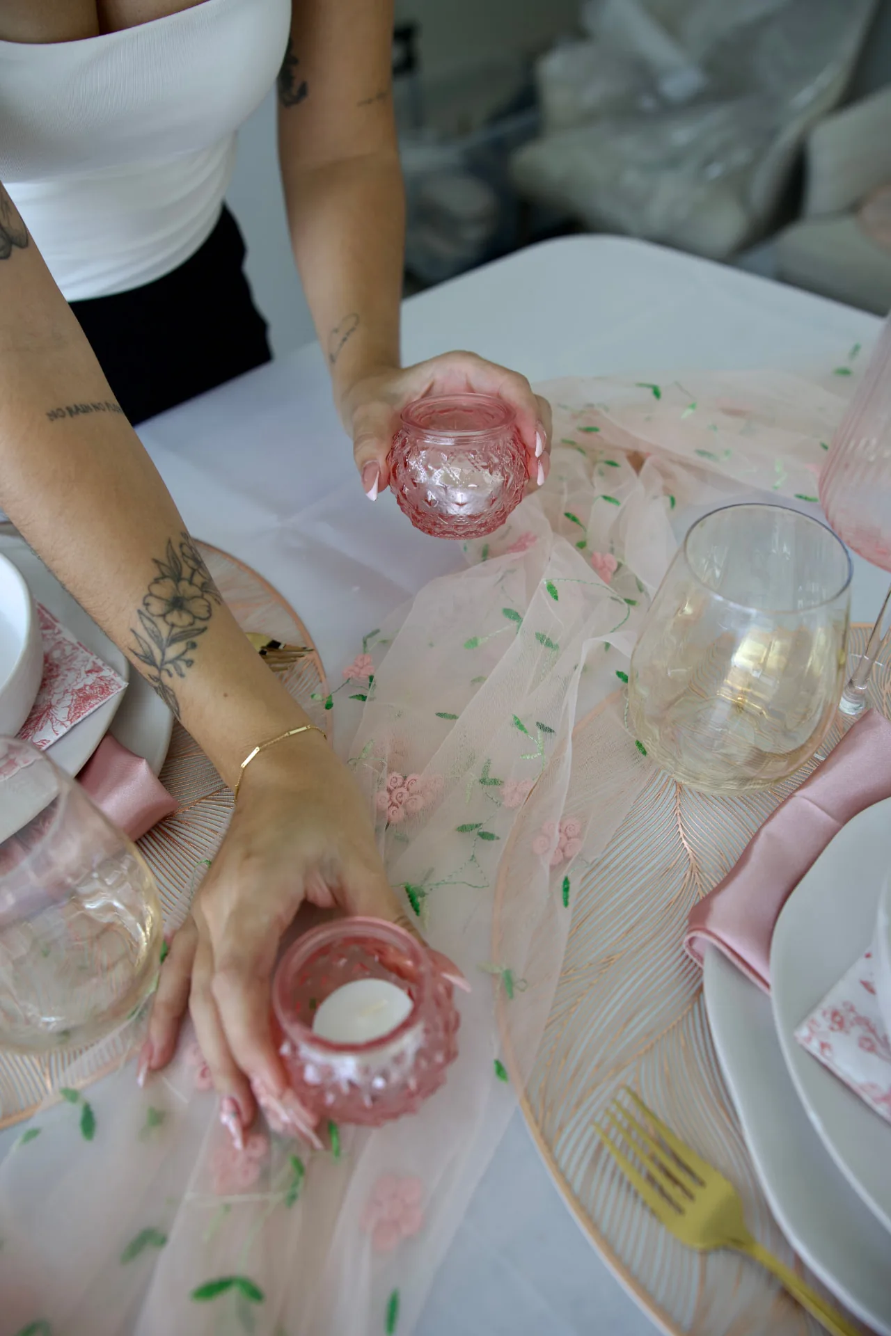Stylist placing blush glass votives on an embroidered tulle runner